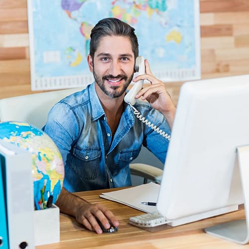 A man sitting at his desk talking on the phone.