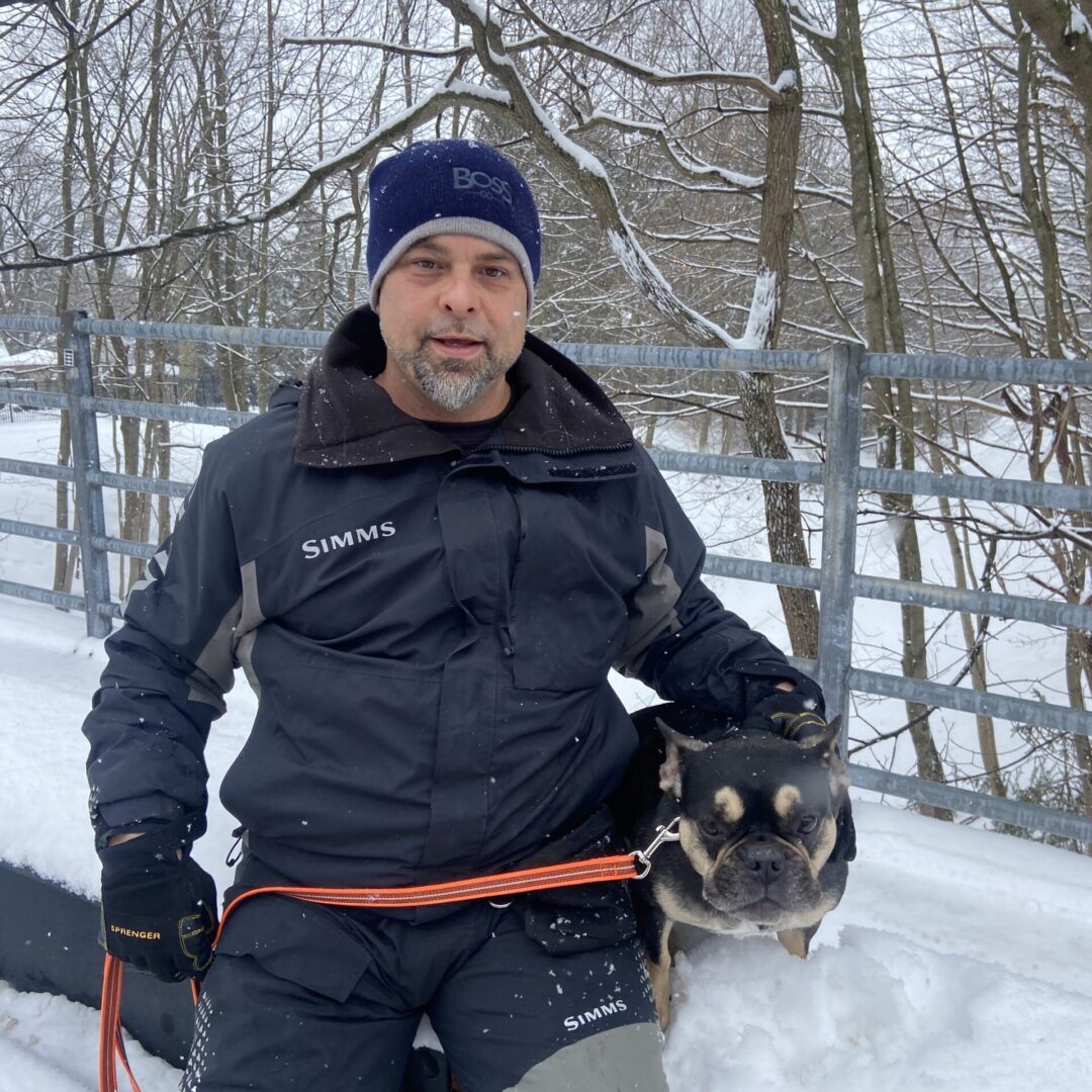 A man holding a dog in the snow.